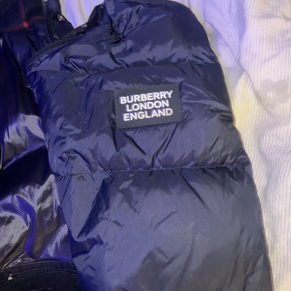 Säljer en stilren svart dunjacka från Burberry. Jackan har en klassisk rutig insida och är perfekt för kyliga dagar. Den har långa ärmar och en snygg design med Burberry-logga på ärmen. Passar perfekt för dig som vill ha både stil och komfort kan bli väst och funkar perfekt till sommaren skriv vid intresse eller om ni har frågor priset går att diskutera👍🏽. Takit.