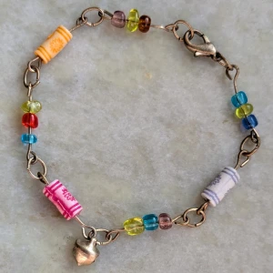 Färgglatt armband med pärlor och berlocker - Charmigt armband med färgglada pärlor i blått, rött, gult och brunt. Armbandet har små berlocker och en säker klolås. Perfekt för att lägga till en färgklick till din stil!