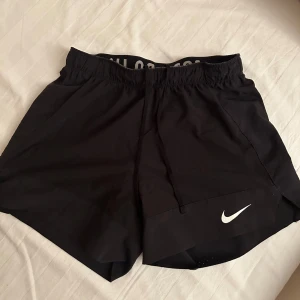 Svarta träningsshorts från Nike - Säljer svarta träningsshorts från Nike. Perfekta för sport och träning med en bekväm passform och elastisk midja. Strlk XS, säljer då de inte kommer till användning. 