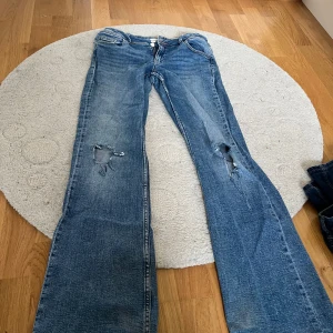 Blå jeans från Gina Tricot, stl 170 - Snygga blå jeans från Gina Tricot, stl 170 med slitna detaljer på benen med snygga fickor baktill. Är lite slitna. Priset kan diskuteras.