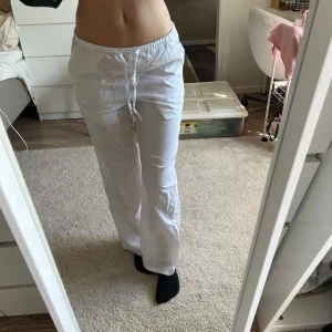 Vita linnebyxor från Gina Tricot - Säljer ett par fräscha vita linnebyxor från Gina Tricot med avslappnad passform och snörning i midjan. Byxorna har elastisk midja och raka ben, perfekta för chill dagar eller när du vill ha en clean look. Superlätta och luftiga, passar grymt till sneakers eller sandaler.