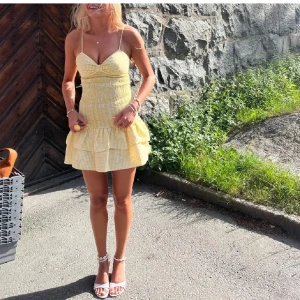 Gul rutig kortklänning med volanger - Supersöt gul och vit rutig klänning med smala axelband. Andvänd enbart vid foto tillfället det vill säga som ny, mina bilder 💛💛