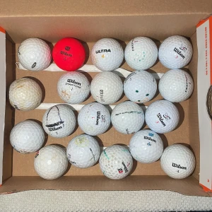 Wilson golfbollar i C/D klass - Samling med begagnade Wilson golfbollar, perfekt för dig som vill börja spela golf eller fylla på din samling. Blandade modeller och nummer, vissa med färgmarkeringar. Passar både nybörjare och erfarna golfare som vill ha prisvärda bollar.
