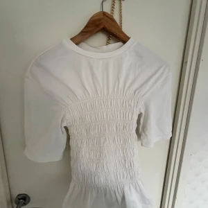 Vit smockad blus Other stories - Superfin vit blus med smockad midja och volangkant nedtill. Supertreding och jättefin.  Tillverkad i mjuk bomull som känns skön mot huden.