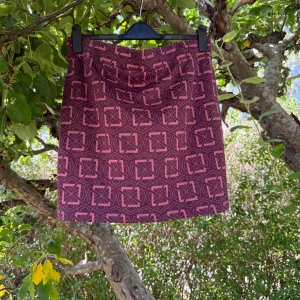 Mörklila kortkjol med geometriskt mönster - Snygg mörklila/rosa kortkjol med rosa geometriskt mönster. Storlek L. Kjolen har en rak och enkel form som ger en clean look. Materialet känns mjukt och följsamt, perfekt för dig som gillar att sticka ut med coola detaljer och färger. Mycket fint skick, jag hittar inga synliga anmärkningar eller defekter. Den har aldrig använts men bara ledat i garderoben och i förrådet ett bra tag.  