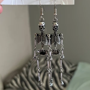 Riktigt coola skelettörhängen - Unika och coola örhängen i form av detaljerade skelett. De är silvriga och har rörliga leder som ger en edgy vibe. Perfekta för dig som vill sticka ut och addera lite attitude till din stil. Passar extra bra till halloween eller när du vill ha något annorlunda.
