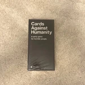 Cards Against Humanity - Cards Against Humanity är det ultimata partykortsspelet för dig som gillar mörk humor och galna skratt. Perfekt för fester med vänner där ni vill utmana varandras gränser och ha riktigt roligt tillsammans. Internationell utgåva.