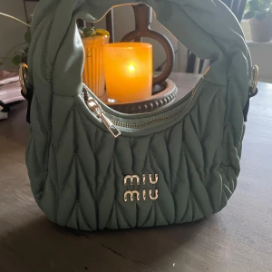 Grön quiltad handväska  - Supersnygg handväska  i en mjuk grön färg. Väskan är quiltad med coola detaljer i guld, har en dragkedja och en matchande axelrem. Perfekt storlek för det viktigaste och riktigt trendig look.