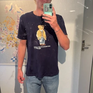 Mörkblå Polo Bear t-shirt Ralph Lauren - Snygg mörkblå t-shirt från Ralph Lauren med Polo Bear-tryck på bröstet. Modellen är custom slim fit och i strl L, den är i princip i ny skick.