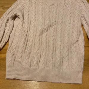 Ljusbeige kabelstickad tröja - Säljer en mysig ljusbeige kabelstickad tröja med klassiskt flätmönster på framsidan. Tröjan har rund hals, ribbade muddar och långa ärmar. Perfekt för dig som gillar stilrena och tidlösa plagg med lite chunky känsla.