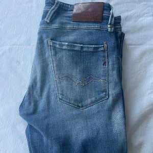Replay Anbass slim fit jeans blå - Säljer ett par Replay Anbass slim fit jeans i klassisk blå tvätt med snygga slitningar och detaljer på fickorna. Storlek 32 passar den som är runt 180. Skick 9/10 knappast använda!