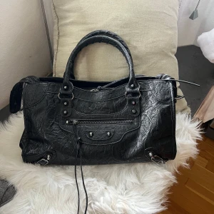 Väska med dragkedja och nitar - Använt fåtal gånger, ena ”snörningen” på en av dragkedjan har försvunnit (se bild 2) och en liten smink fläck inuti väskan(bild 5). Annars i väldigt bra skick.