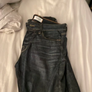 Mörkblå Slim Glenn jeans från Jack & Jones - Säljer ett par mörkblå Slim Glenn jeans från Jack & Jones. De har klassisk femficksdesign, orangea sömmar och en slim passform som sitter snyggt längs benen. Jeansen är tillverkade i jeansmaterial och har en stilren look med diskret logga på bakfickan.