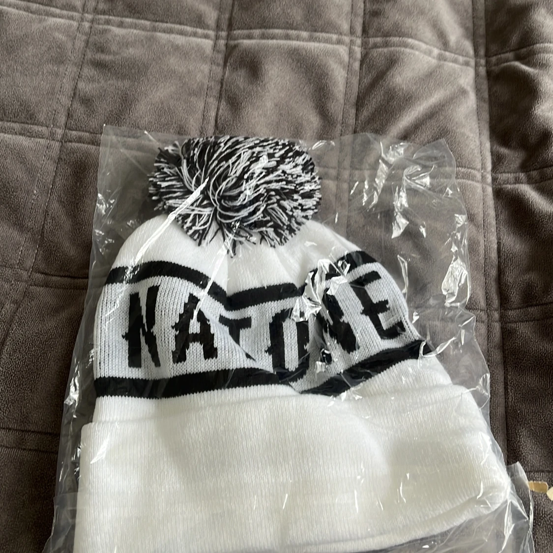 Vit mössa med svart text och tofs