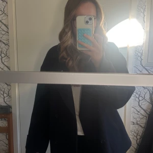 Mörkblå kappa från Nelly - Säljer en stilren mörkblå kappa från Nelly med bred krage och dubbelknäppning framtill. Kappan har långa ärmar och en klassisk, lite loose passform. Den är använd en höst så lite nopprig men annars inga defekter. Den är i strl xs men stor i storleken. Perfekt nu till skolstarten och hösten!🍁📚