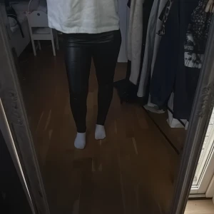 Svarta tighta lackbyxor från Boland - Säljer ett par svarta, glansiga lackbyxor från Boland i storlek M/L. De har en riktigt slim och tight passform som sitter snyggt mot kroppen. Perfekta om du vill ha en edgy look med skinande finish.