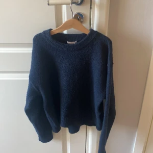 Mörkblå stickad tröja Gina Tricot - Mysig mörkblå stickad tröja från Gina Tricot i storlek 158/164. Tröjan har en loose passform med rund hals och långa ärmar. Materialet är mjukt och fluffigt, perfekt för kyliga dagar. Enkel och stilren design som är lätt att matcha med jeans eller kjol.