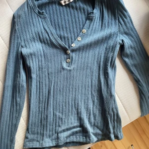 Blå ribbad långärmad tröja AWARE - Säljer en blå ribbad långärmad tröja från AWARE med v-ringning och fyra vita knappar framtill. Tröjan är rätt ny, i xs och sitter kroppsnära💗