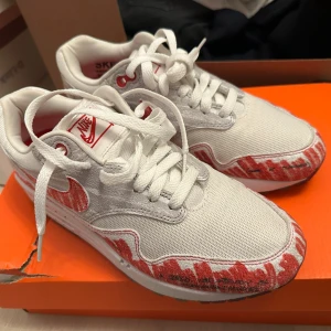 Nike Air Max 1 tinker Sketch to Shelf skor 38 - Nike Air Max 1 Sketch to Shelf sneakers i vit mesh och mocka med röda handritade detaljer och Swoosh. Unik design med synliga skisslinjer och transparent sula med rutmönster. Skorna har snörning och platt sula, perfekt för dig som gillar statement pieces.