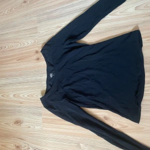Svart långärmad tröja från 157 - En basic svart långärmad tröja från 157 i mjuk bomull med lite stretch. Enkel och stilren modell med rund halsringning, perfekt att matcha med jeans eller kjol. Materialet är 95% bomull och 5% elastan för en skön passform.