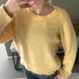Gul stickad tröja från Samsøe  - Supermjuk gul stickad tröja från Samsøe med rund halsringning och ribbade muddar. Perfekt för lager-på-lager och ger en fräsch vibe till jeans eller kjol. Långärmad och i en ljus gul ton som känns vårig och fräsch.