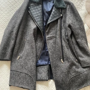 Grå ulljacka från Rag & Bone  - Snygg grå ulljacka från Rag & Bone med coola detaljer i svart skinn vid krage och insida. Jackan har långa ärmar, dragkedjor framtill och på fickorna samt quiltad insida vid bröstet. Perfekt för dig som gillar en stilren men edgy look. Nypris 10000kr.