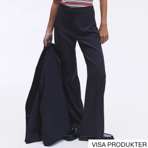 Svarta vida kostymbyxor - Snygga svarta kostymbyxor med hög midja och vida ben. Byxorna har pressveck framtill och en klassisk, stilren look som passar perfekt till en dressad outfit. Tillverkade i ett mjukt och följsamt material för en bekväm känsla hela dagen.