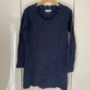 Mörkblå stickad tröja Odd Molly - Supersöt mörkblå stickad tröja från Odd Molly med virkade blommor runt ringningen och snyggt mönster nertill. Ungefär som en stor small i storlek. Ull, alpacka och akryl. 