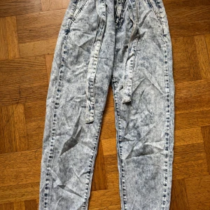Acid wash jeans med knytband Amisu - Snygga acid wash jeans från Amisu med knytband i midjan. Byxorna har en ljusgrå tvättad look, raka ben och klassiska fickor både fram och bak. Perfekta för dig som gillar en avslappnad och trendig stil.