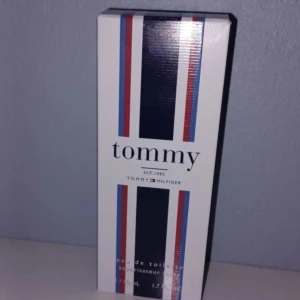 Tommy Hilfiger Tommy EdT 50ml - Fräsch parfym från Tommy Hilfiger, Tommy EdT 50ml. Flaskan är transparent med silverfärgad metallkork och svart text. Kartongen är vit med marinblå, röda och ljusblå ränder, klassisk och stilren design. Perfekt för dig som gillar sportiga och fräscha dofter.