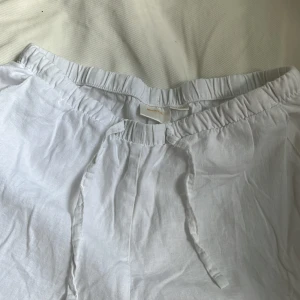 Vita linnebyxor från Gina Tricot - Snygga och luftiga vita linnebyxor från Gina Tricot med resår i midjan och knytband. Perfekta för varma dagar och ger en chill vibe. Byxorna är raka i modellen och har en avslappnad passform.