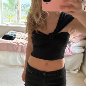 Svart one shoulder top -  svart croppad topp med one shoulder och knutdetalj framtill. Passsar till många tillfällen!!