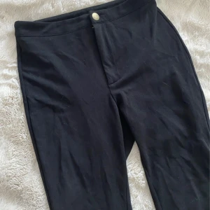 Svarta leggings från Shein - Svarta leggings från Shein med hög midja och stretchigt material. De har en enkel design med knapp framtill och är perfekta för en chill och bekväm stil. Passar till allt och är superenkla att matcha.