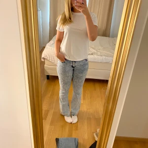 Ljusblå bootcut jeans - Säljer ett par ljusblå bootcut jeans med stentvättad look och lätt slitna detaljer. Jeansen har normal passform och klassisk femficksdesign. Perfekta för dig som gillar sånna jeans. 
