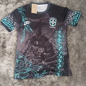 Nike Brasil fotbollströja svart/turkos S - Unik Brasilien fotbollströja från Nike med svart bas, turkosa detaljer och leopardmönster på ärmarna. Tryck med Kristusstatyn och tropiska blad, CBF-emblem på bröstet. Tillverkad i lätt Dri-FIT-material som andas.