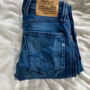 Blå Replay Anbass jeans slim fit - Snygga blå jeans från Replay, modell Anbass. Jeansen har en slim passform med klassisk femficksdesign och tydliga Replay-detaljer på fickorna. Tillverkade i stretchig denim för extra komfort och med normal midja. Perfekta för en avslappnad men stilren look.