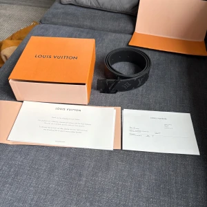 LV Initiales Matte Black Belt - Äkta LV bälte, 40 mm. Köpt förra månaden (som man ser på papprena), helt oanvända. Skick är 10/10 , inga defekter.  Nypris är 5200. Säljer för 4000 eller högst budande. Värdepapper, låda, påse etc medföljer. Kan både mötas upp i Stockholm, eller frakta.  Funkar för både män och kvinnor, men kanske främst män.