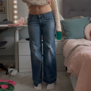 Blå wide fit jeans strl 28 - Säljer ett par blå wide fit jeans i storlek 28. Jeansen har låg midja, klassisk femficksdesign och raka, vida ben. Materialet är klassisk denim med  kontrastsömmar. Midjemått: 38cm