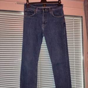 Blå raka jeans från Lee - Klassiska blå jeans från Lee med rak passform och normal midja. Jeansen har fem fickor, gylf med dragkedja och Lee-logga på bakfickan. Perfekta för en clean och tidlös look.