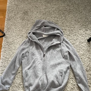 Grå hoodie i kashmir från Sayless - Mjuk och lyxig grå hoodie från Sayless i 100% kashmir. Tröjan har dragkedja framtill, huva med snörning och två fickor. Perfekt för dig som vill ha en stilren och bekväm look med premiumkänsla. Helt ny, bara testat den! Strl XXS
