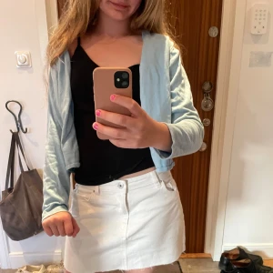 Vit jeanskjol med fickor - Snygg vit kort jeanskjol med klassiska fickor fram och bak samt knapp och dragkedja i midjan. Perfekt för en fräsch och enkel look, lätt att matcha med olika toppar och jackor.