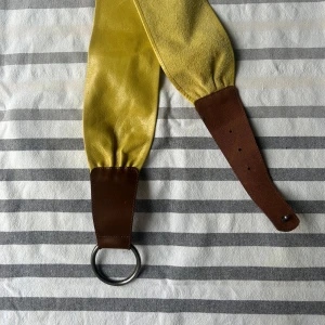 Brett gult och brunt skärp i skinn - Gult midjebälte i skinn med silverfärgad ring som spänne. 