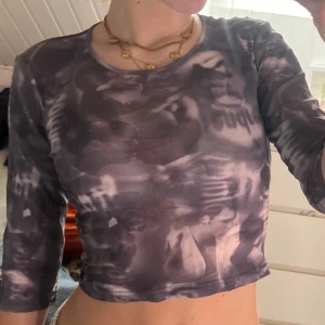 Grå mesh topp med tryck från InScene - Säljer en grå mesh topp från InScene med unikt tryck i svartvitt. Toppen har rund halsringning och trekvartsärm, är croppad och sitter tight. Perfekt för dig som gillar edgy och konstnärliga plagg.