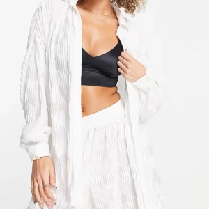 Vita vida byxor med plisserat mönster, samt skjortan till, set. - Säljer ett vitt set med skjorta och superfräscha byxor med med snyggt plisserat mönster. Byxorna är höga i midjan och har en riktigt vid passform som ger en chill och luftig känsla. Perfekta för varma dagar och en clean look. Nypris ca 1100 kr.