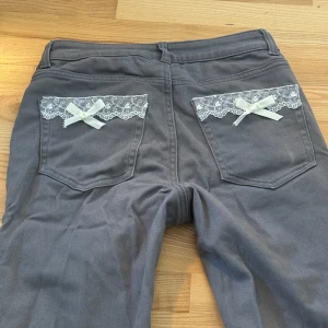 Jeans med spets och rosett - jeans från h&m i storlek 36 med egensydd design. midjemåttet rätt över är 34 cm och innerbenslängden är 76 cm. använd ”köp nu”. 10/6-2025