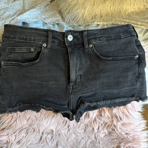 Svarta jeansshorts med fransig kant - Snygga svarta jeansshorts med rå, fransig kant nertill. De är tillverkade i mjukt jeanstyg och har knapp- och dragkedjestängning framtill. Säljer även ett par blåa💖
