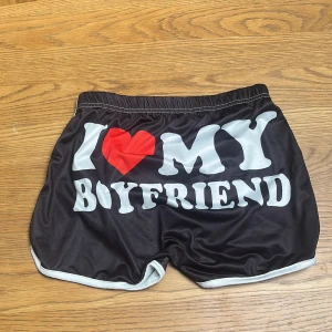 Svarta  I ❤️ MY BOYFRIEND shorts - Svarta shorts med  ”I ❤️MY BOYFRIEND” tryck från exet. Köpta från nån hemsida. De e glansiga o stretchiga. Strl xs o aldrig använda. Vill ba bli av med så fort som möjligt så grabbar in o klicka hem den till din tjej😊