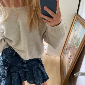 Sandfärgad stickad tröja - Supermysig stickad tröja i beige/sandfärg. Supernajs över en klänning/kjol och har en urringning som kan läggas över axeln💕💕