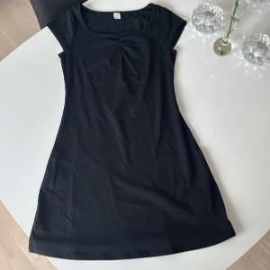 Svart kortklänning från SHEIN Teen - En svart, enkel och stilren kortklänning från shein. Klänningen har korta ärmar, rundad halsringning och en lätt rynkning framtill vid bysten. Använd endast 1 gång.