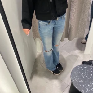 Ljusblå bootcut jeans med slitningar - Säljer ett par ljusblå jeans med bootcut-modell och slitna detaljer vid knäna. Jeansen har klassiska fickor både fram och bak samt en snygg tvätt som ger en cool, avslappnad vibe. Perfekta för dig som gillar en trendig och bekväm stil.